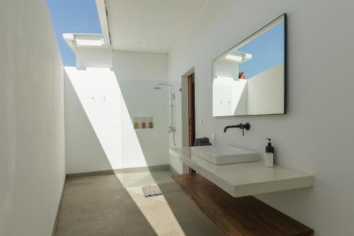 a white bathroom with a sink and a mirror at Villa Papì Uluwatu 1 in Bingin Beach