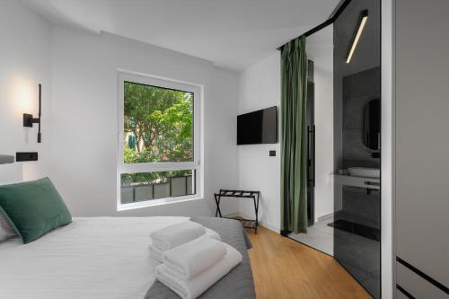 a white bedroom with a bed and a window at Residence Maru' in Rovinj