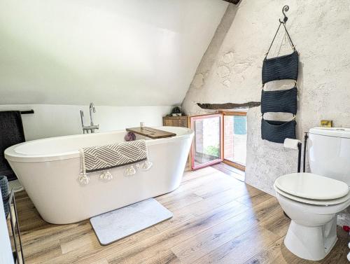a bathroom with a white tub and a toilet at Bluedothotels location France in Magnac-Laval