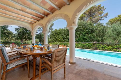an outdoor dining area with a table and chairs and a swimming pool at Casa Gotmar 132 in El Port