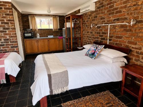 a bedroom with a bed and a brick wall at Chargo River Lodge in Colesberg
