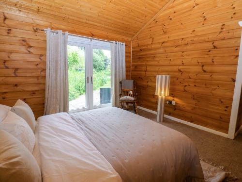 a bedroom with a bed and a window in a log cabin at Bulrush Cabin in Carlisle