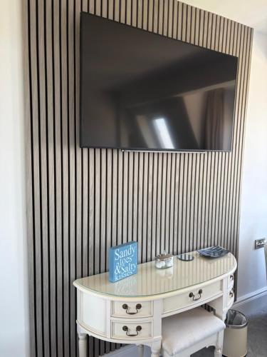 a room with a table with a tv on a wall at Lazy Waves in Newquay