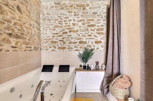 a bathroom with a tub and a stone wall at Jacuzzi de charme pour 2 in Nîmes