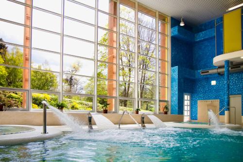 a pool with water jets in a building with windows at Spa Hotel Garni Löwenstein in Konstantinovy Lázně