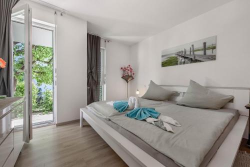 a white bedroom with a large bed and a window at Ferienwohnung Annabelle in Bodman-Ludwigshafen