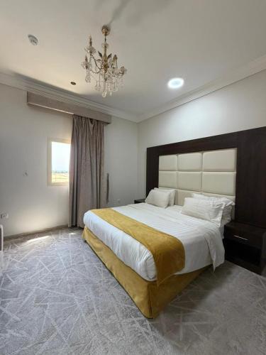 a bedroom with a large bed and a chandelier at شاطئ الياسمين للشقق الفندقية in Yanbu
