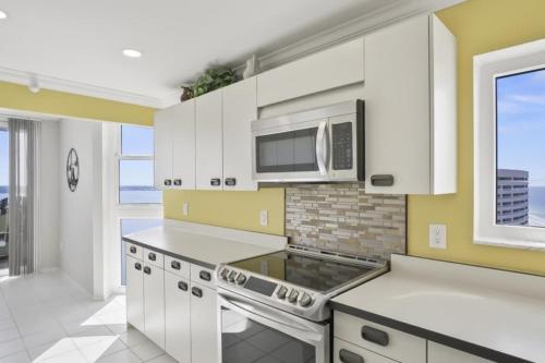 a kitchen with white cabinets and a microwave at Two Bedroom Corner Condo with Panoramic Gulf Views in Clearwater Beach