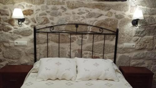 Cama en habitación de piedra con 2 almohadas en Casa Da Chousa, en Combarro