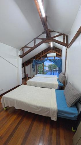 three beds in a room with wooden floors at Feelgood dive resort in Basbas