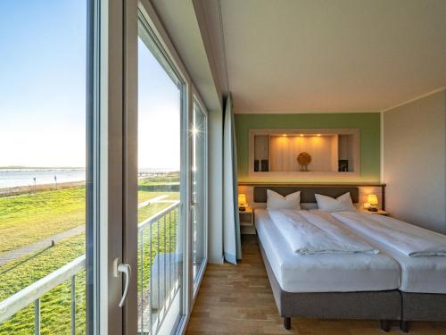 a bedroom with a bed and a view of the ocean at BE BIO Hotel be natural - direkt am Wasser in Tönning