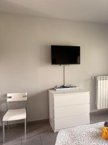 a bedroom with a tv and a white dresser and a chair at los jardines las rozas in Las Rozas
