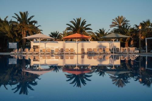 a swimming pool with chairs and umbrellas at Camping Estival Vendrell Platja in Comarruga
