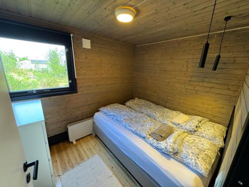 a bed in a small room with a window at Hyggeli in Vadsø