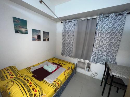 a small bedroom with a yellow bed and a window at Sea Residences in Manila