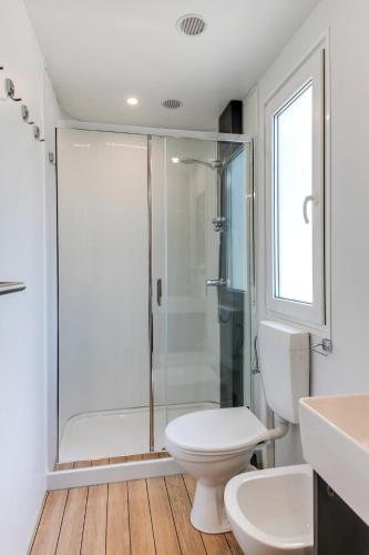 a white bathroom with a shower and a toilet at Camping Adria Riccione in Riccione