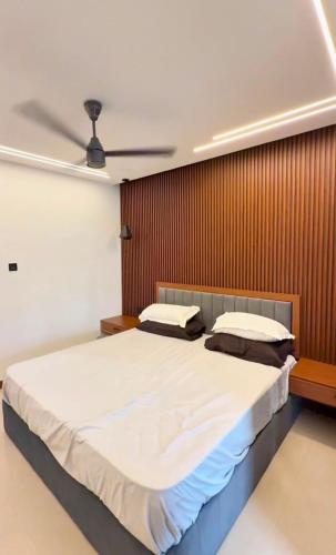 a bedroom with a large bed with a wooden wall at Luxe Kochi Flat Backwater Views in Cochin
