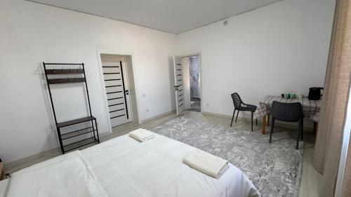 a white bedroom with a bed and a table and chairs at Guest House Alim in Karakol