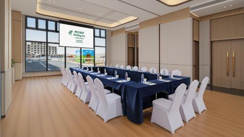 a conference room with a long table and white chairs at Holiday Inn Bayanbulak by IHG in Bayanbulak