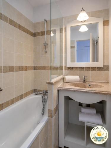 a bathroom with a tub and a sink and a bath tubermottermott at Magiuli Village du Rouret in Grospierres