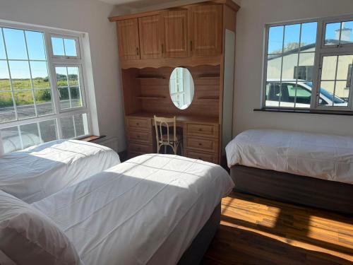 two beds in a room with two windows at Denmar Spacious coastal bungaow in Cleedagh Bridge