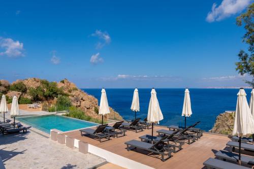 a pool with chairs and umbrellas and the ocean at Soluna Forte Sea Living Suites in Palaiokastro