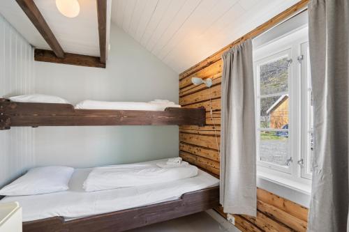 ein Schlafzimmer mit zwei Etagenbetten und einem Fenster in der Unterkunft Åsebua - Renovated rorbu with seaview in Sørvågen