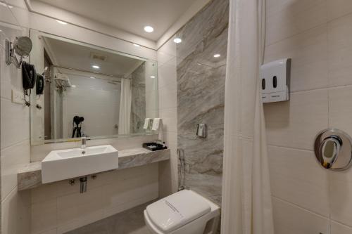 a bathroom with a sink and a toilet and a mirror at Hotel Suba Galaxy Mumbai in Mumbai