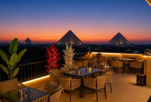 a restaurant with tables and chairs on a balcony with pyramids at New Gardenia Pyramids - Rooftop in Cairo