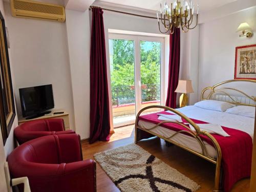 a bedroom with a bed and a chair and a window at Vila Smarald Apartments in Neptun
