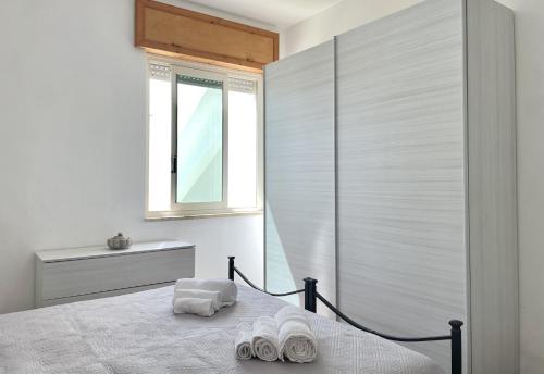 a bedroom with a bed with white sheets and a window at CASA CALIPSO - Casa a pochi passi dal mare delle Maldive del Salento in Salve