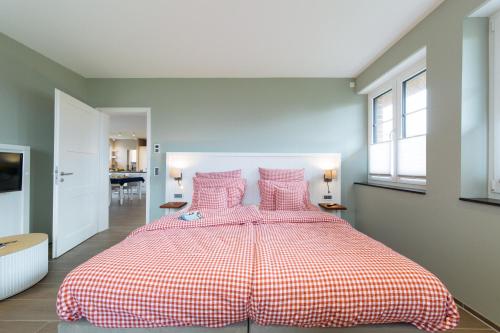 a bedroom with a large bed with pink pillows at SunCliff Lodge - exklusive private Sauna, Sanarium, Kamin und Meerblick in Dranske