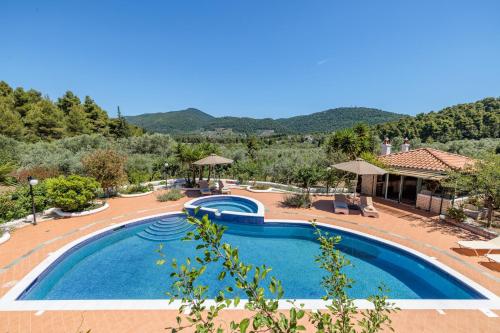 a pool at a resort with mountains in the background at Nature Grand Estate - Spacious Villa with Pool in Skopelos Town