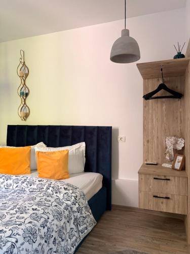 a bedroom with a bed with a blue headboard and orange pillows at Casa Saga proprietate administrata de o gazda particulara in Mangalia