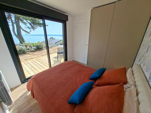 a bedroom with a bed with blue pillows and a large window at Le chalet Ker Yann Vue mer Locquirec in Locquirec