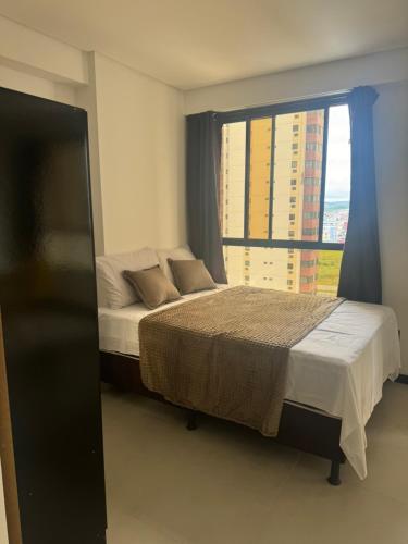 a bedroom with a bed and a large window at Flat no bairro universitário in Caruaru