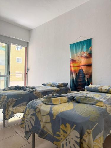 three beds in a room with a painting on the wall at AS Orikum 2 in Orikum