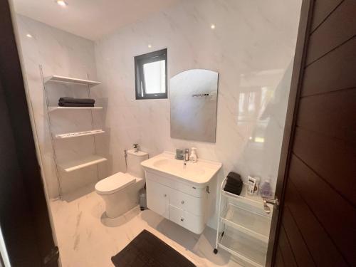 a white bathroom with a sink and a toilet at Villa Mirada Maenam - Renovated Four Bedroom with Private Pool in Nathon Bay