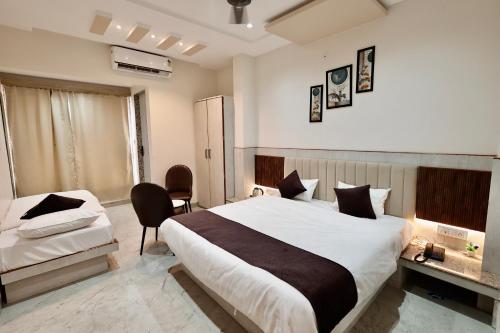 a hotel room with a large bed and a chair at Hotel Maniratna Premium in Indore