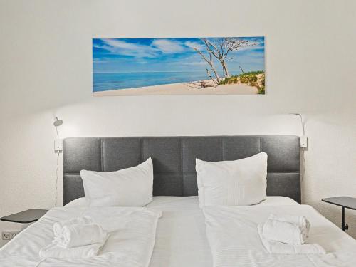 a bed with two white pillows and a picture of a beach at Apartment Düneneck App-17 by Interhome in Zempin