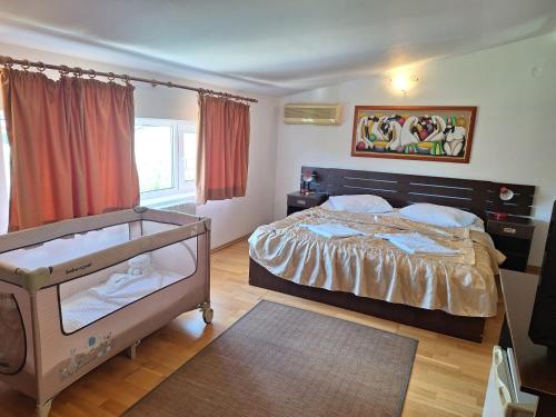 a bedroom with a bed and a crib in it at Vila Diamant in Neptun