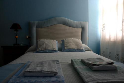 Un dormitorio azul con una cama con toallas. en Pension Bajamar en Ladrido