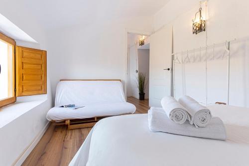 a white bedroom with two beds and a chair at Campo and relax Málaga country house in Málaga
