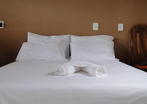 Una cama blanca con almohadas blancas y toallas. en Pousada Flores en Itaúnas