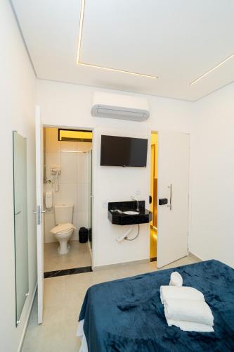 a bedroom with a bed and a toilet and a tv at AIRPORT HOTEL GRU LTDa in Guarulhos