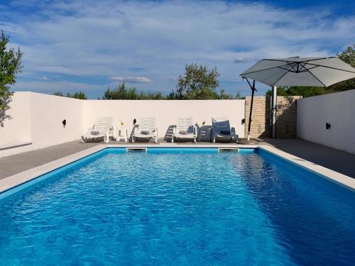 a swimming pool with chairs and an umbrella at Holiday Home Karlo by Interhome in Posedarje