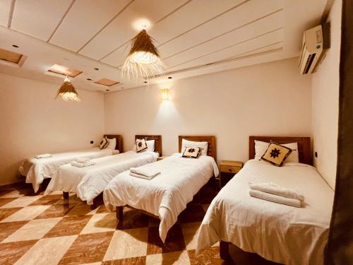 three beds in a room with a checkered floor at Dar Surfana Surf Camp & Yoga Tamraght in Aourir