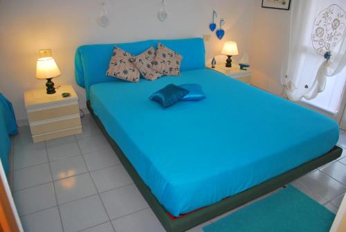 een blauw bed in een kamer met 2 lampen bij Appartamenti Gelsomino in Marina di Campo