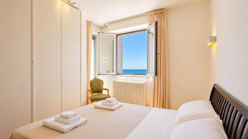 a bedroom with a bed and a window and a chair at SkyMare - Beachfront Sea View Apartment in Porto San Giorgio