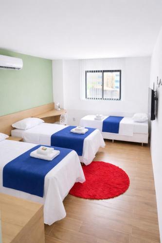 a room with three beds and a red rug at Carambola CoLiving in Olinda